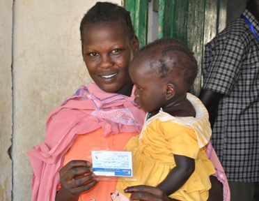 A mother shows off her punched registration card, a sign that she has voted.