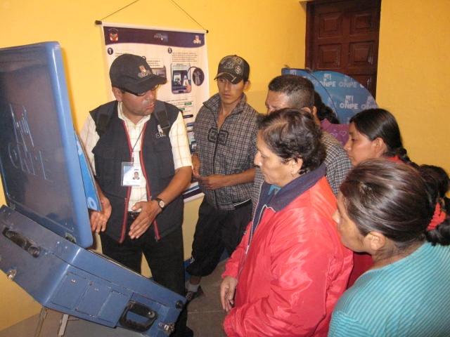 An ONPE official introduces voters to the new electronic voting machine.
