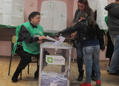 A young girl helps her mother cast a ballot.