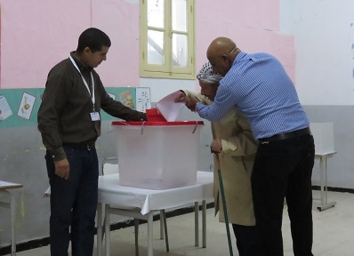 A blind voter gets help putting his ballot in the ballot box.