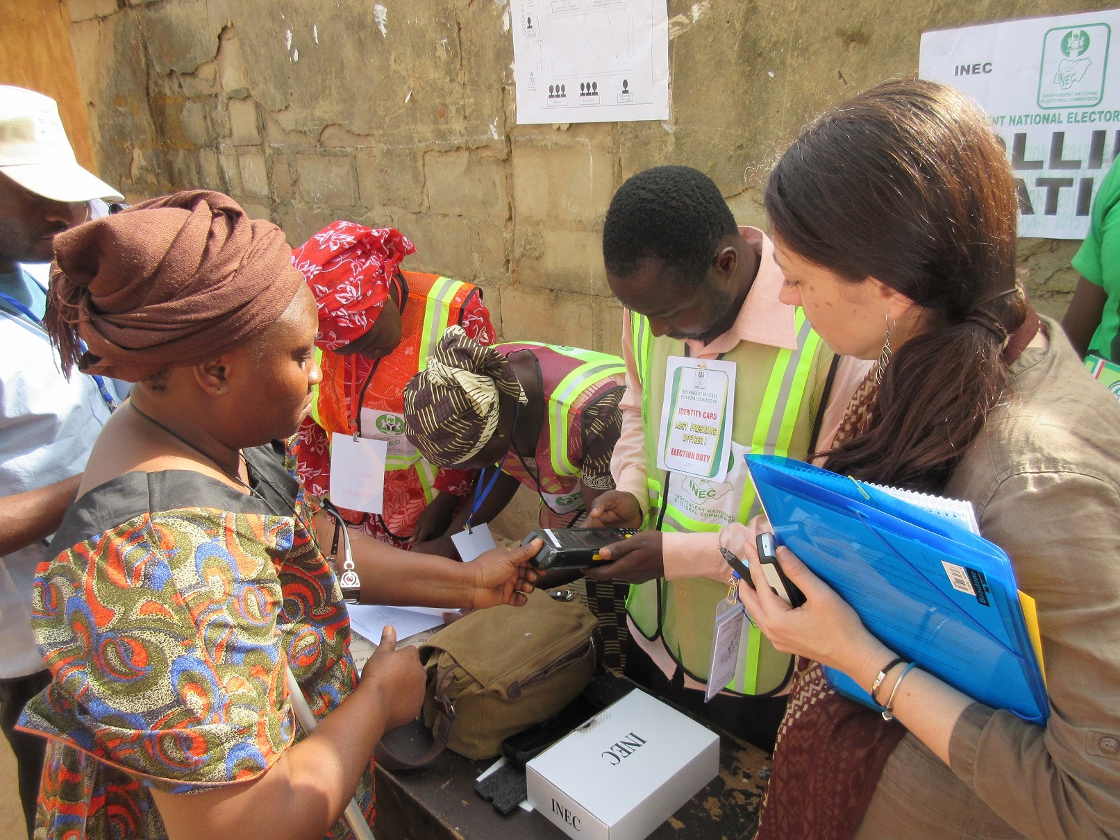 An IRI observer watches as a poll officer checks a voter’s fingerprint.