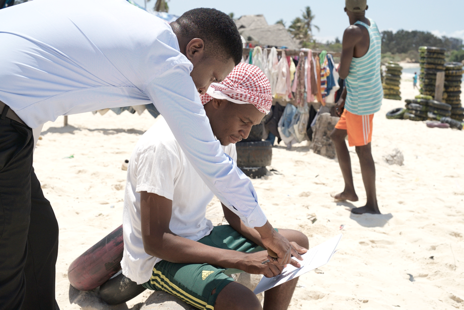 Tony Alfred guides another Tanzanian through the Katiba Yangu booklet on their country’s Constitution.