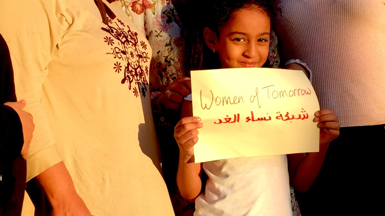 The daughter of a WSN coordinator holds up a sign displaying the network’s new name, Chabakat Nissa Al Ghad or Women of Tomorrow