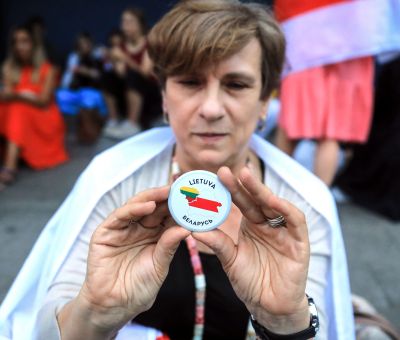 A woman stands with a button with Lithuania and Belarus country shapes on it during a protest