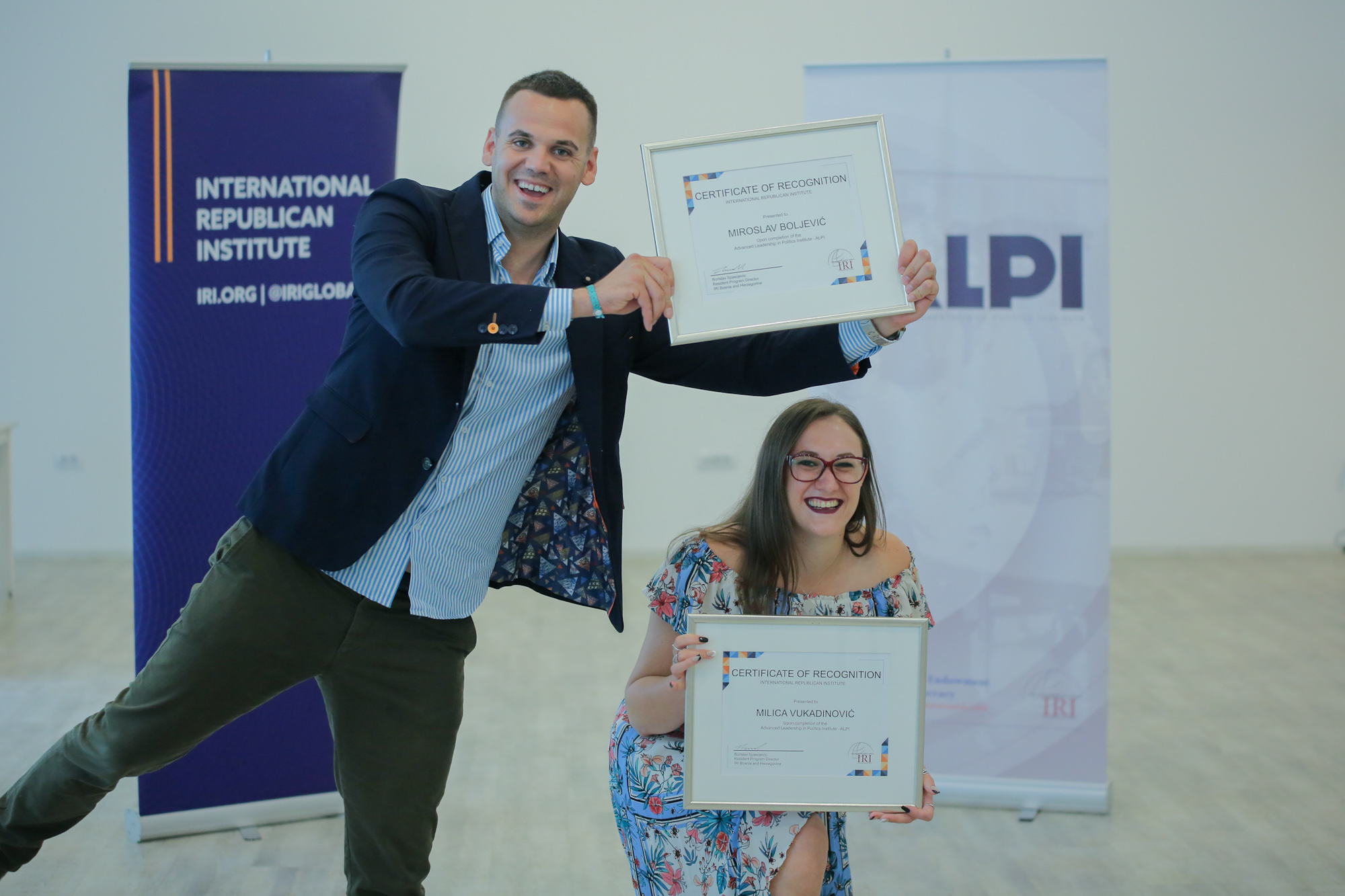 Two people hold up certificates