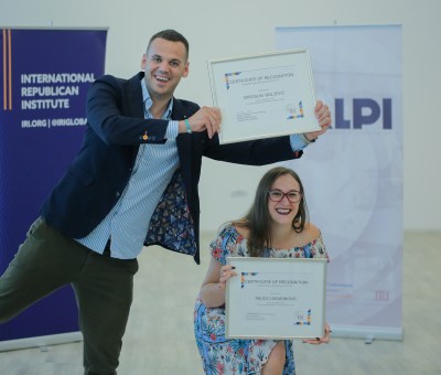 Two people hold up certificates