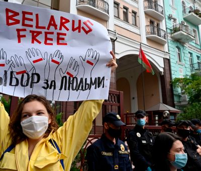 A lady holds up a sign in protest; the sign says "Belarus Free"