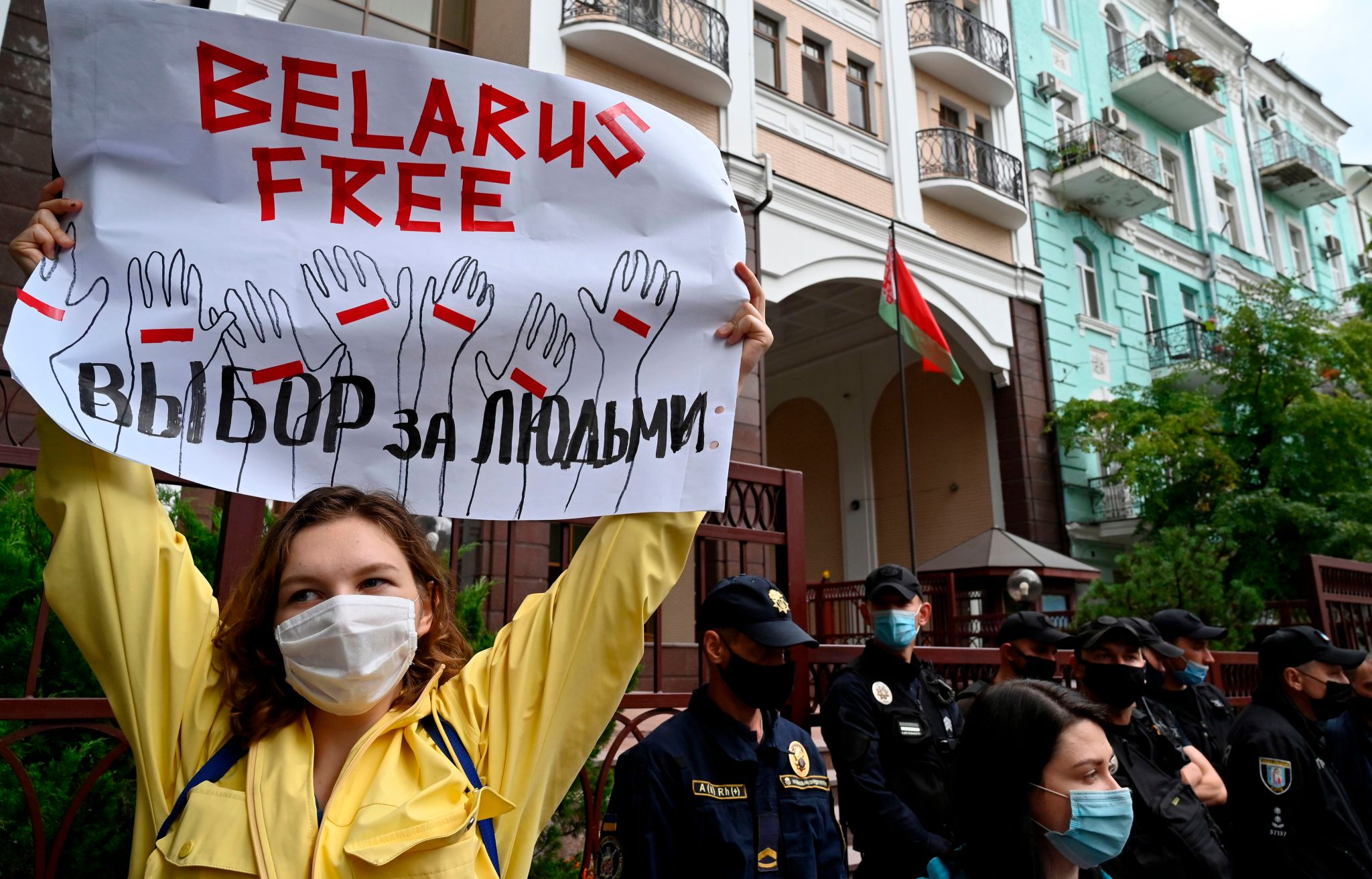 A lady holds up a sign in protest; the sign says "Belarus Free"