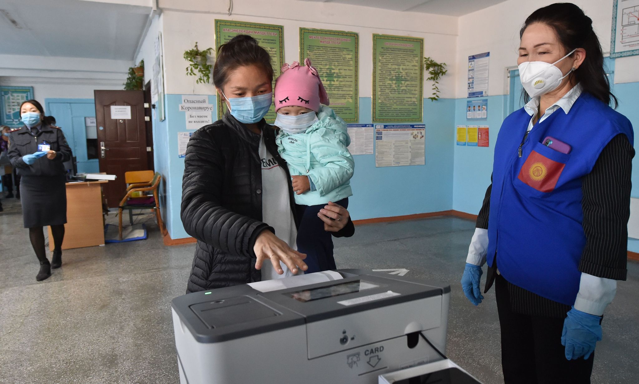A woman holding a child casts her ballot