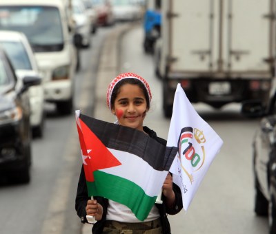 A girl holds a Jordanian national flag