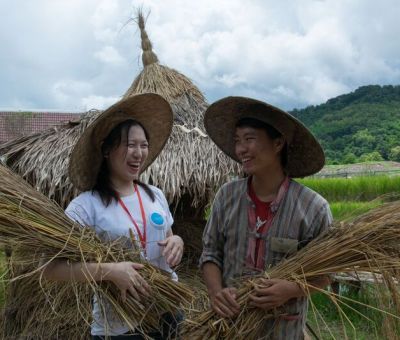 Two people in straw hats smiling at each other wile holding grain