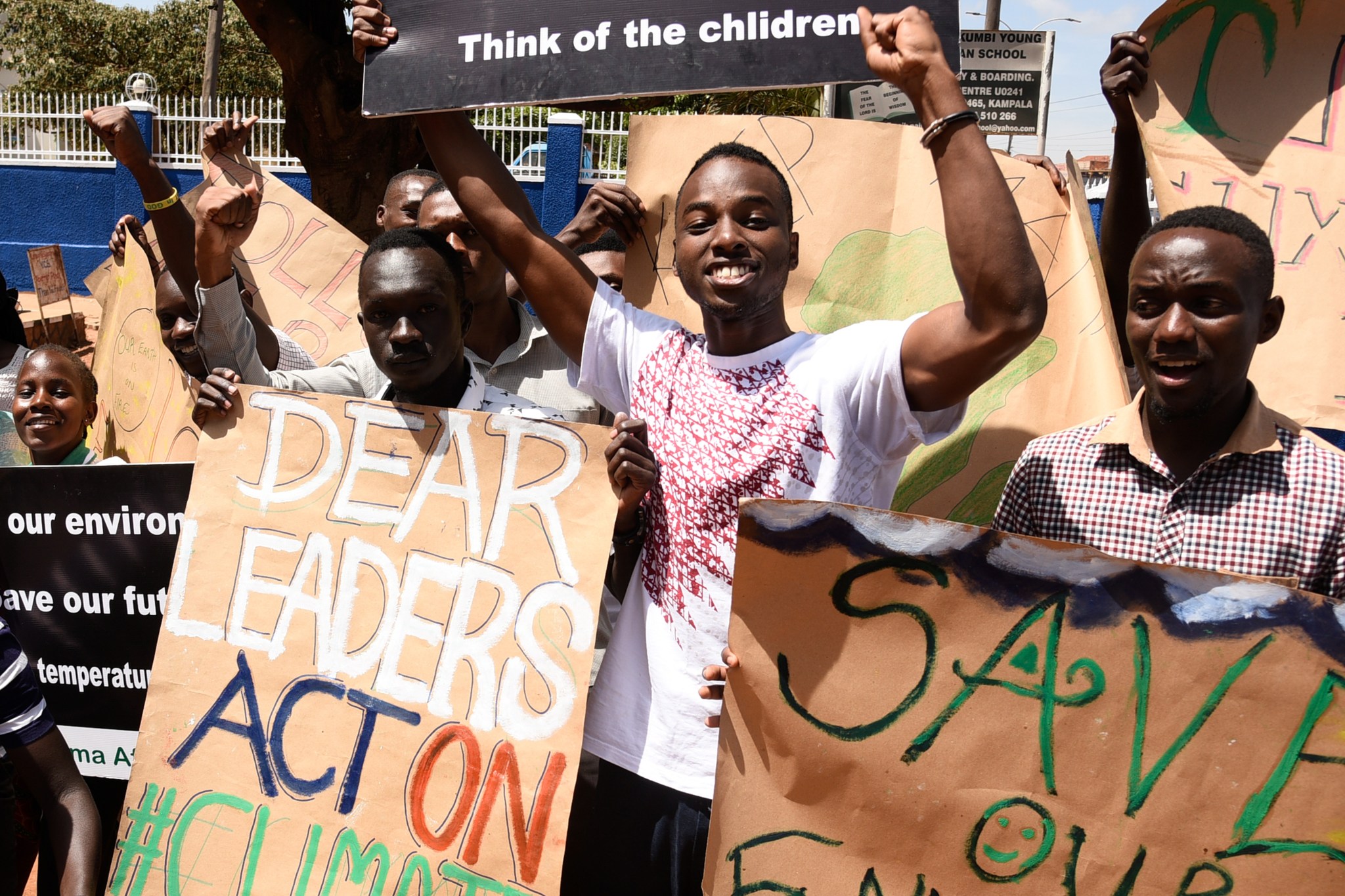 Youth hold up posters, calling leaders to address climate change