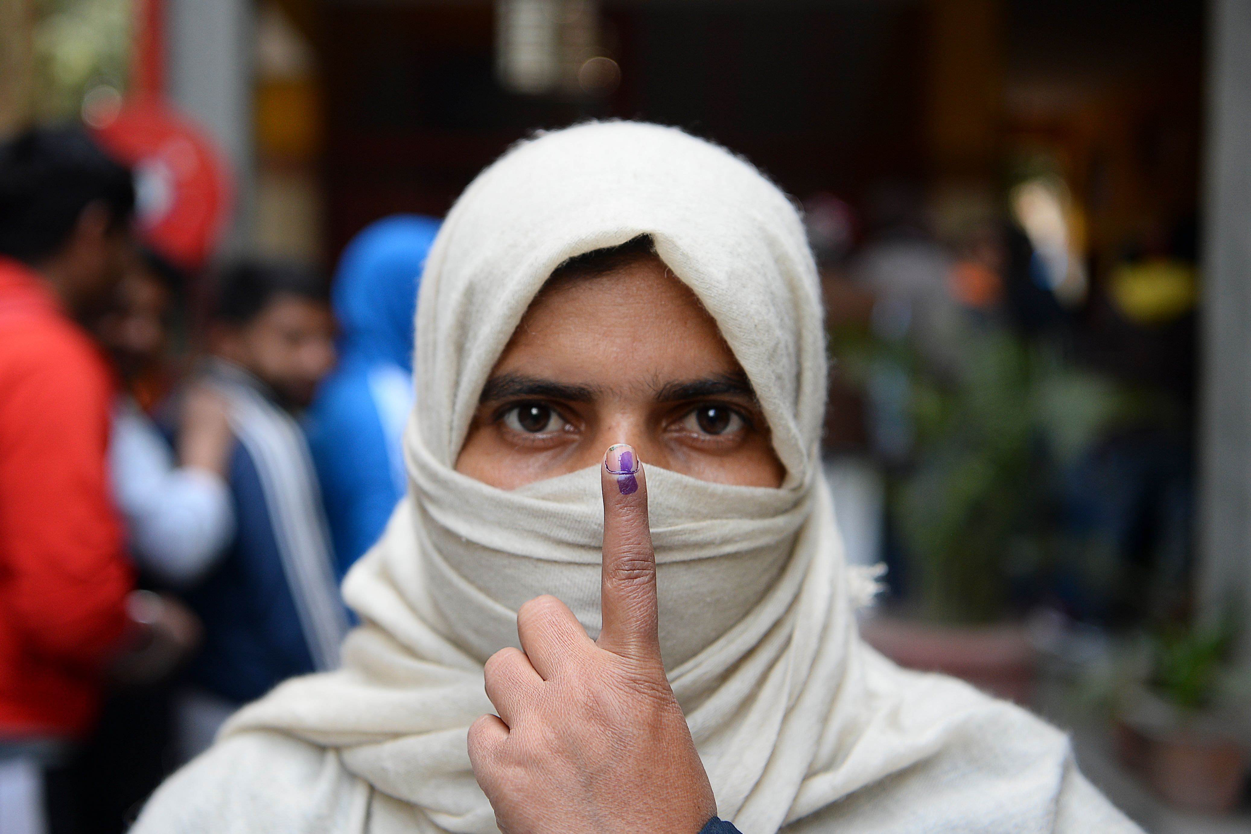 A woman shows her ink-marked finger after casting her vote