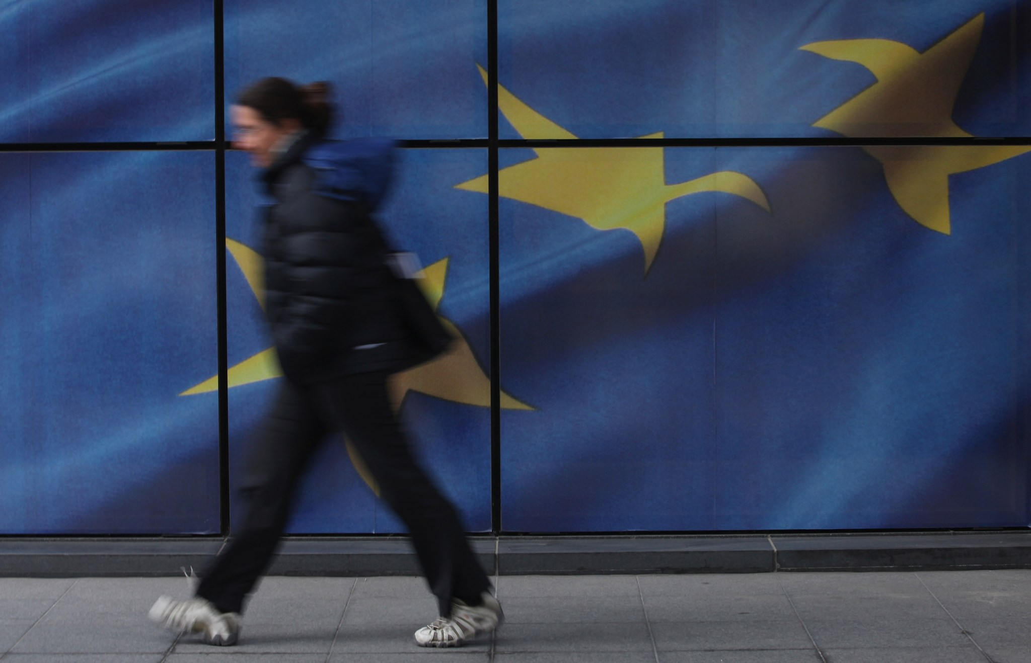 A lady walking in front of the EU flag