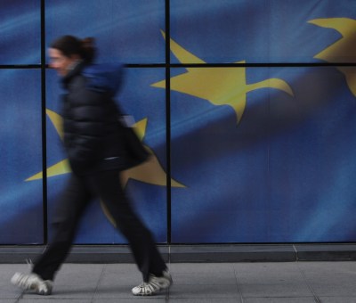 A lady walking in front of the EU flag