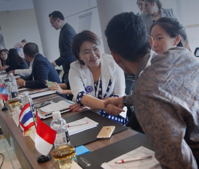 Two people shaking hands with flags in background