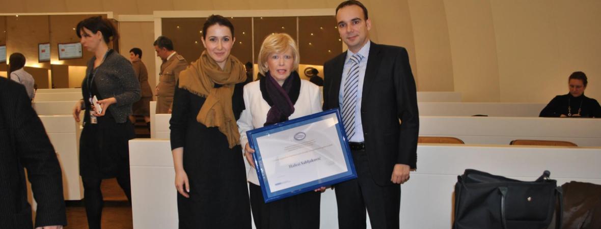 Three people stand for a group photo at an awards event